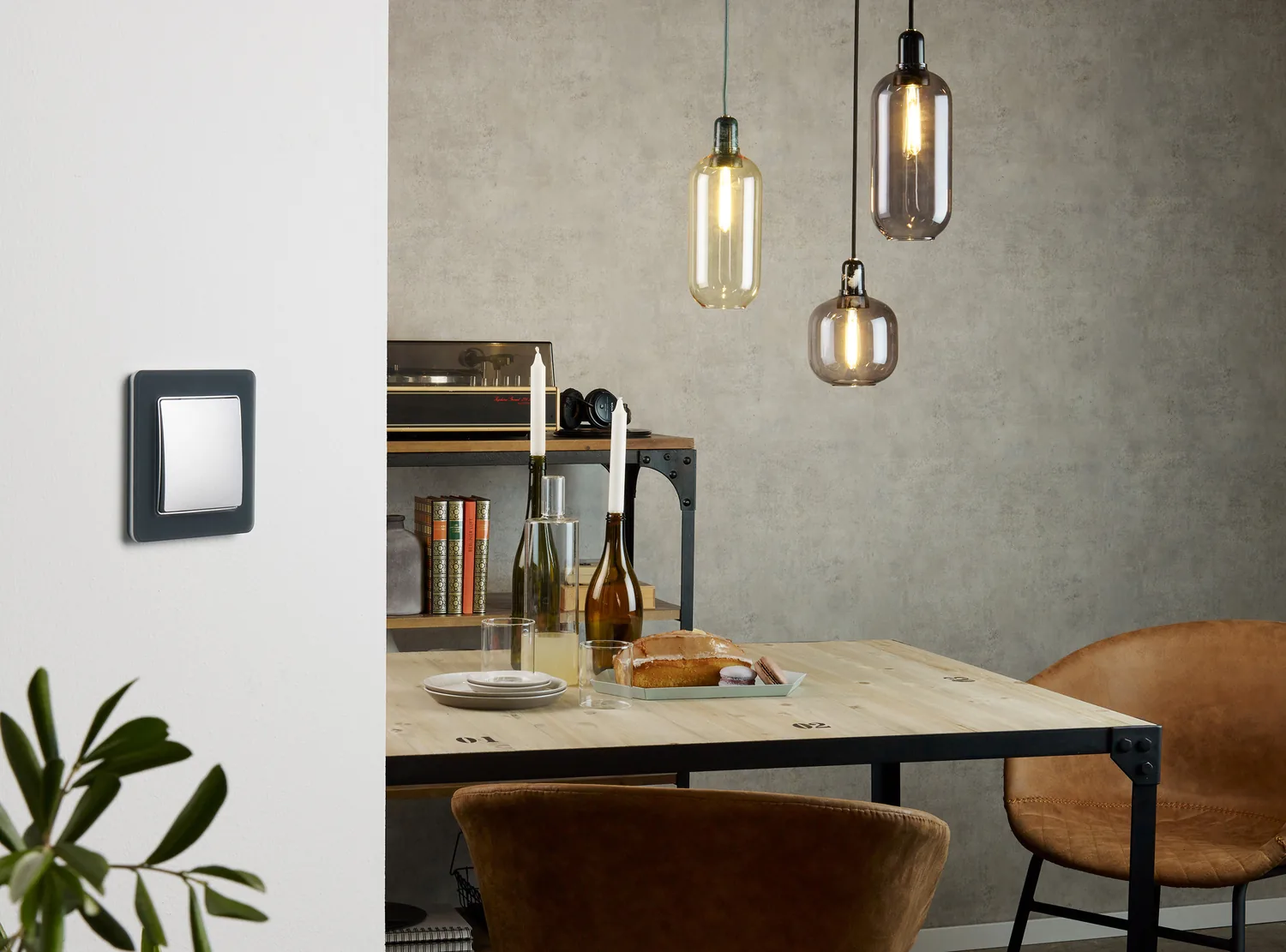 Вимикач Sedna Design у чорно-сірій рамці біля обіднього столу